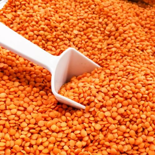 Heap of organic red dal or dhall with ladle in bucket