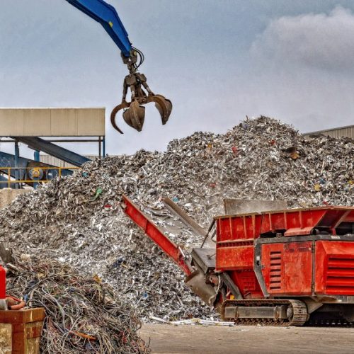 A grab crane lifting large amounts of scrap metal into a machine which reduces the sixe of the waste metal for further recycling processes.